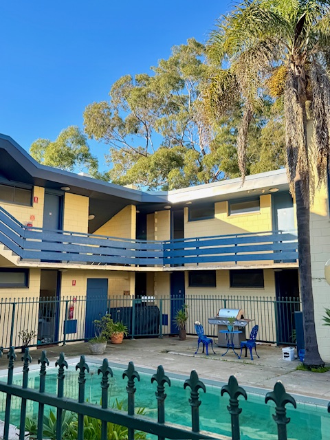 Pathfinder Motel Kew courtyard with pool, palms and blue balcony railings
